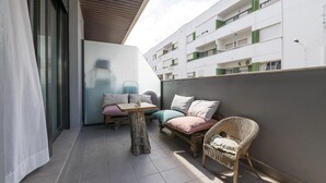 Un balcon avec une table, des meubles en osier et une vue sur un immeuble à plusieurs étages.