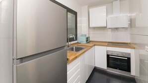 Une cuisine moderne dotée d’un réfrigérateur en acier inoxydable, d’un four encastré et d’un micro-ondes posés sur un plan de travail en bois.