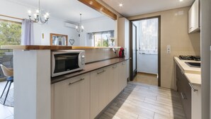 Une cuisine moderne équipée d’un four à micro-ondes encastré, d’une cuisinière à gaz et d’armoires en bois.