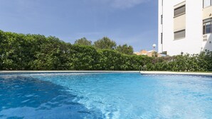 Une piscine d’un bleu éclatant, avec un bâtiment blanc et de la verdure en arrière-plan.