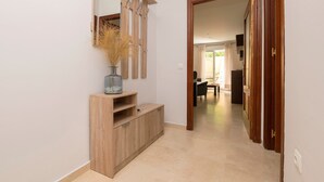 Un corridoio con un tavolo consolle in legno, uno specchio e un vaso con piante essiccate.