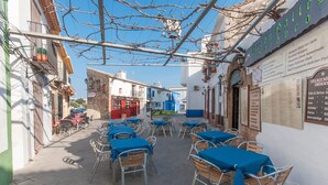 An outdoor café with tables and chairs, a menu board, and buildings in the background. - Cascades in D nia With 2 Bedrooms and 1 Bathrooms (Denia)