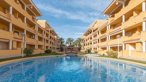 A hotel with a central swimming pool, multiple balconies, and a clear sky. - Cascades in D nia With 2 Bedrooms and 1 Bathrooms (Denia)