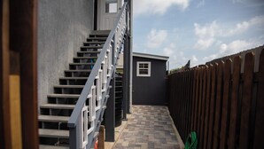 Un stretto sentiero esterno conduce a un piccolo edificio con una finestra e una porta.