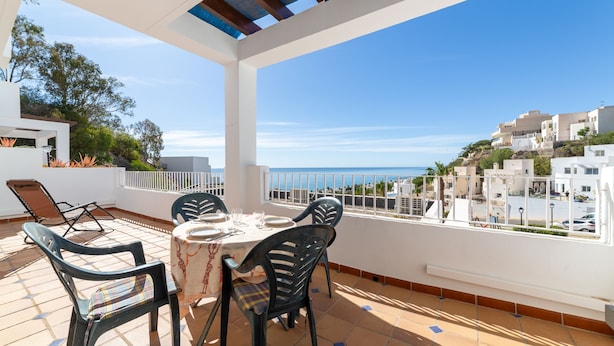 Una terraza con mesa y sillas, con vistas a un pueblo costero.