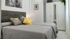 A modern bedroom with two beds, a wardrobe, and artwork on the walls. - El Poeta in Fuengirola (Fuengirola)