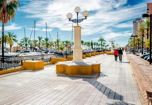 A paved walkway with a central monument, palm trees, and a marina with boats. - El Poeta in Fuengirola (Fuengirola)