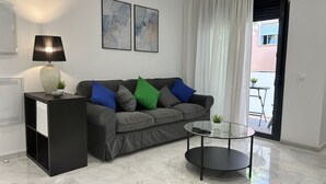 A modern living room with a grey sofa, a glass coffee table, a lamp, and two abstract paintings on the wall. - El Poeta in Fuengirola (Fuengirola)