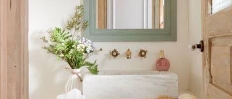 A bathroom with a white sink, a green-framed mirror, and two wicker baskets below the sink.