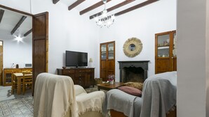 A cozy living room with a fireplace, wooden furniture, and a television. - Casc Antic in Javea With 2 Bedrooms and 1 Bathrooms (Javea)
