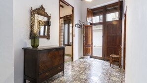 A hallway with a wooden cabinet, a mirror, and a door with a window. - Casc Antic in Javea With 2 Bedrooms and 1 Bathrooms (Javea)