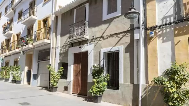 A row of traditional Mediterranean-style buildings with balconies, potted plants, and a clear sky. - Casc Antic in Javea With 2 Bedrooms and 1 Bathrooms (Javea)