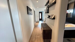 Un pasillo moderno con suelo de madera, un banco y estantes empotrados decorados con objetos decorativos.