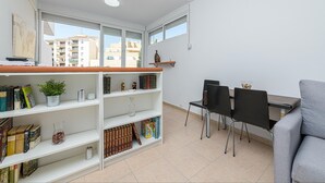 Una sala de estar moderna con comedor, que incluye una estantería, una mesa de centro y un sofá gris.
