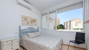 Un dormitorio con cama, una silla, cómoda y ventana, además de un mapa del mundo en la pared.