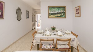 Een eetzaal met een tafel gedekt voor vier personen, stoelen, een kroonluchter en lijstwerken aan de wanden.