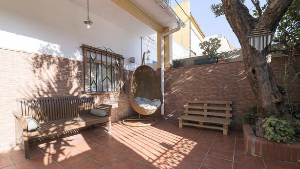 A patio with a wooden bench, a hanging chair, and a wall-mounted lantern. - Casa Del Olivo in Algeciras (Algeciras)