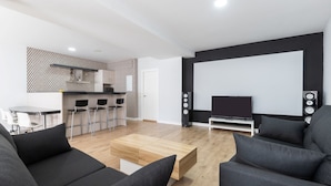 A modern living room with a black sofa, a wooden coffee table, and a TV on a stand. There is a kitchen area with a patterned backsplash and a dining table with chairs. - Clipper in Alhaurin de la Torre (Alhaurin de la Torre)