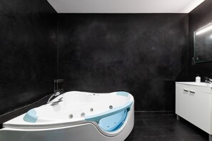 A modern bathroom with a freestanding bathtub, a white vanity with a mirror, and black tiled walls. - Clipper in Alhaurin de la Torre (Alhaurin de la Torre)