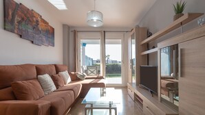 A modern living room with a brown sofa, a glass coffee table, and a flat-screen TV on a wooden stand. - Casa Carmen in Bah a Dorada (Estepona)