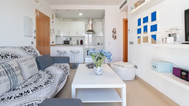 Un salon moderne avec un canapé à motifs, une table basse blanche et un vase de fleurs.