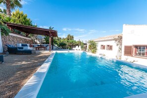 A swimming pool with a pergola, outdoor seating, and a stone wall. - Tramuntana in Trencall (Javea)