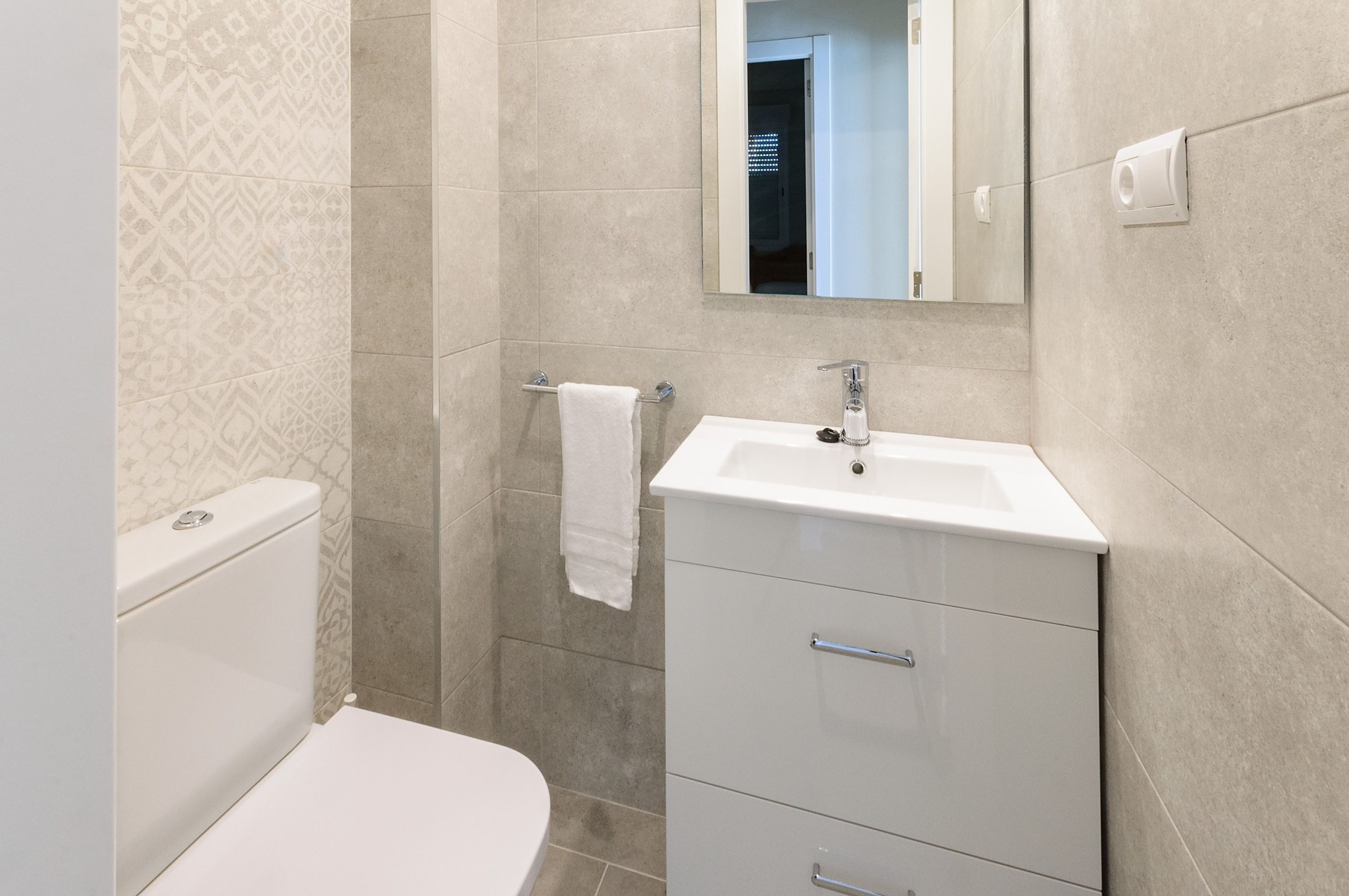 Une salle de bain moderne avec des toilettes, un lavabo et un miroir.