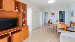 A living room with a TV, wooden cabinets, a dining area with a table and chairs, and a hallway leading to other rooms. - Turia in Tavernes de la Valldigna (Tavernes de la Valldigna)