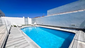 A rectangular swimming pool with a tiled deck, surrounded by white walls and a metal fence. - Poniente in Chiclana de la Frontera (Chiclana de la Frontera)