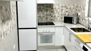 A compact kitchen with a refrigerator, stove, microwave, and sink. - Poniente in Chiclana de la Frontera (Chiclana de la Frontera)