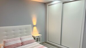 A bedroom with a bed, a nightstand, a wall-mounted light, and a sliding closet door. - Poniente in Chiclana de la Frontera (Chiclana de la Frontera)