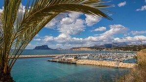 A marina with boats docked, a clear blue sky, and a mountainous landscape in the background. - Poniente in Chiclana de la Frontera (Chiclana de la Frontera)