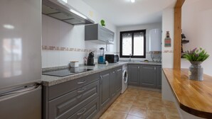 A modern kitchen with grey cabinets, a built-in oven, and a coffee maker. - Tolox 2 in Tolox With 1 Bedrooms and 1 Bathrooms (Tolox)