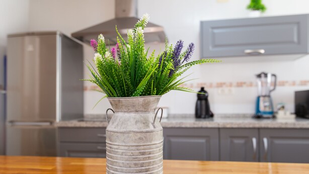 A kitchen with a wooden table, a metal vase with green plants, and a coffee maker. - Tolox 2 in Tolox With 1 Bedrooms and 1 Bathrooms (Tolox)