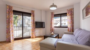 A living room with a sofa, a TV, and a table with a candle. - Tolox 2 in Tolox With 1 Bedrooms and 1 Bathrooms (Tolox)