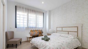 Une chambre à coucher comprenant un lit, une chaise, une petite table et un panneau décoratif mural.