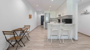 Une cuisine moderne avec des meubles blancs, un micro-ondes noir et une table à manger en bois avec des chaises.