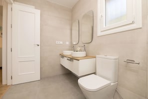 A modern bathroom with a toilet, sink, and mirrors. - Villa Del Sol in Poblado Sancti Petri (Chiclana de la Frontera)