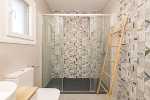 A bathroom with a shower, a toilet, and a wooden counter. - Villa Del Sol in Poblado Sancti Petri (Chiclana de la Frontera)