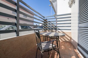 Un balcon avec une table et des chaises, un sol carrelé et une vue sur un immeuble doté de balcons.