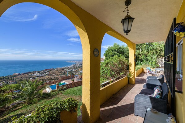 Un patio cubierto con vista al mar, mobiliario exterior y una piscina.