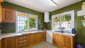Une cuisine avec des meubles en bois, un lave-vaisselle et une fenêtre donnant sur un espace verdoyant.