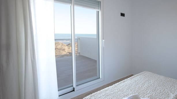 A room with a sliding glass door leading to a balcony with a view of the beach. - Vistamar 1 in Oliva With 2 Bedrooms and 1 Bathrooms (Oliva)