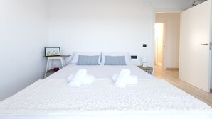 A neatly made bed with white linens and two pillows, a small bedside table with a lamp, and a framed picture on the wall. - Vistamar 1 in Oliva With 2 Bedrooms and 1 Bathrooms (Oliva)