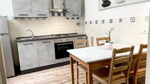 A modern kitchen with grey cabinets, a gas stove, and a wooden dining table with chairs. - Cavour 36 in Firenze (Florence)