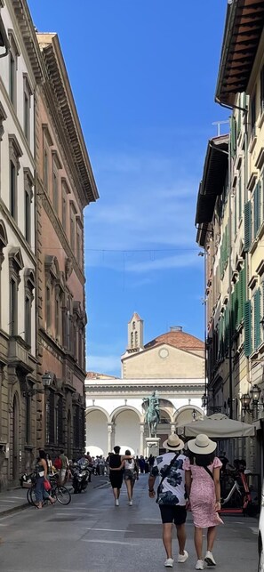 A narrow street with historic buildings, a church with a bell tower, and people walking. - Cavour 36 in Firenze (Florence)