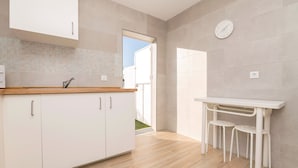 Una cocina moderna con armarios blancos, encimera de madera y una mesa blanca con taburetes.
