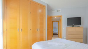 A bedroom with a bed, a wardrobe, a television, and a bathroom visible through an open door. - Villablanca Home in Villablanca (Villablanca)