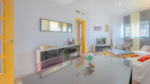 A modern living room with a glass dining table, a sofa, a TV, and a chair. - Villablanca Home in Villablanca (Villablanca)
