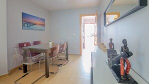 A modern dining area with a glass table and chairs, a painting on the wall, and a small sculpture on the sideboard. - Villablanca Home in Villablanca (Villablanca)